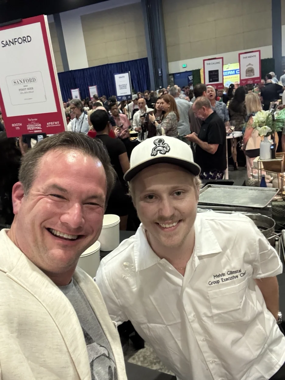 An attendee and a chef in a busy food-and-wine festival hall