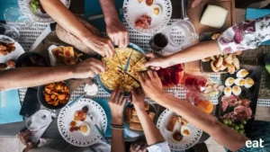 Eatertianment picture with a bunch of hands over food